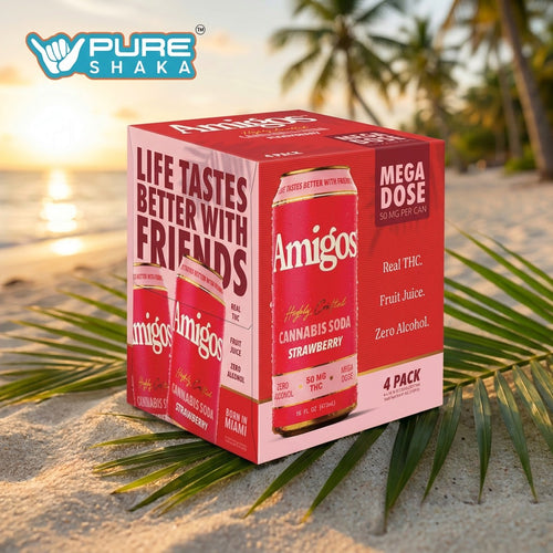 A 4-pack box of Amigos Strawberry CBD softgels, styled on a tropical beach with palm leaves and a sunset background. The packaging is red and pink with white text.